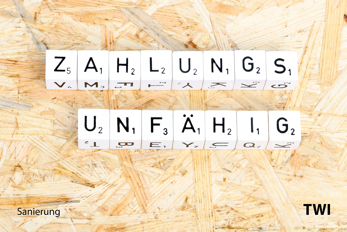 Das Wort zahlungsunfähig mit Buchstabenwürfeln geschrieben. Darunter die Worte: Sanierung - TBI.